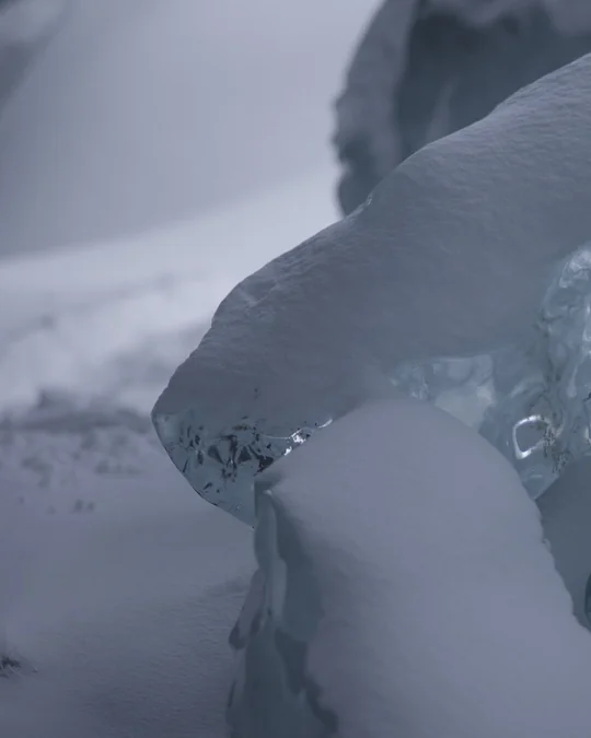 Left half of a curved blue ice formation above snow