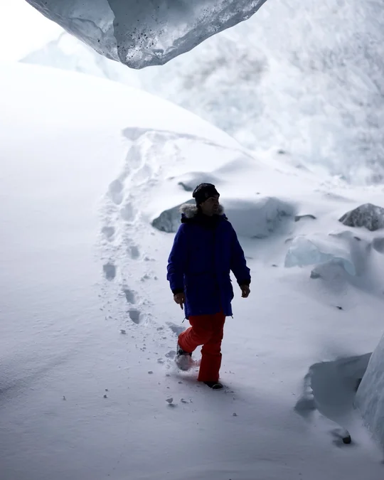 A hiker walks along a snowy path beneath the ice